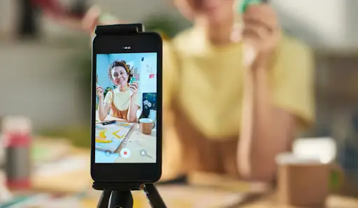 Content creator filming a video review on a smartphone tripod, illustrating how UGC creators produce authentic branded content.