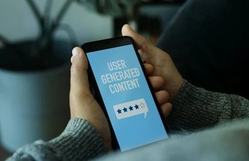 Person holding a smartphone displaying "User Generated Content" with a four-star rating icon, illustrating how Dubai brands source and use UGC