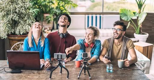Group of content creators recording videos with smartphones, cameras, and laptops