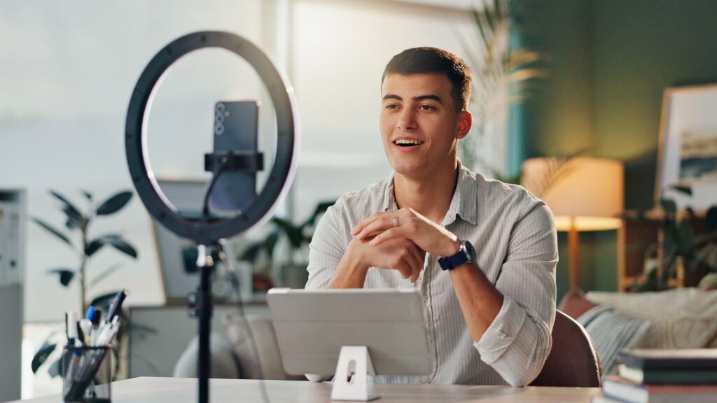 Male influencer recording video content with ring light setup at desk