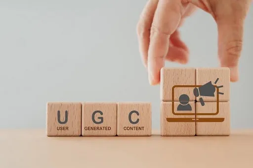 Wooden blocks spelling UGC (User Generated Content) with icon of person and megaphone representing content marketing